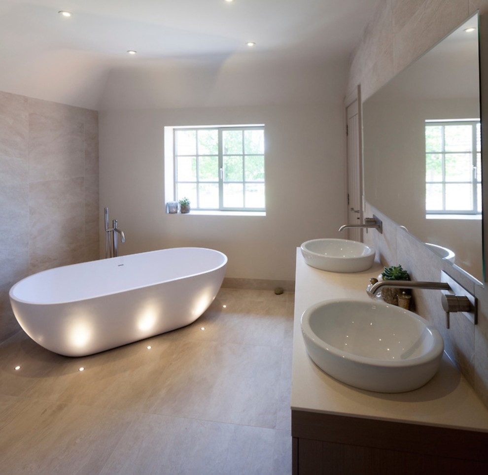 This is an example of a large contemporary ensuite bathroom in West Midlands with flat-panel cabinets, light wood cabinets, a freestanding bath, a walk-in shower, a wall mounted toilet, beige tiles, ceramic tiles, white walls, ceramic flooring, a trough sink and quartz worktops.