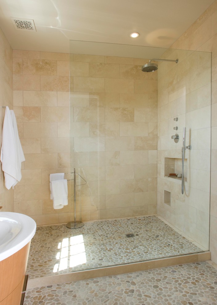 Photo of a large modern shower room bathroom in Portland Maine with a pedestal sink, freestanding cabinets, a walk-in shower, beige tiles, ceramic tiles, beige walls, pebble tile flooring, light wood cabinets and solid surface worktops.