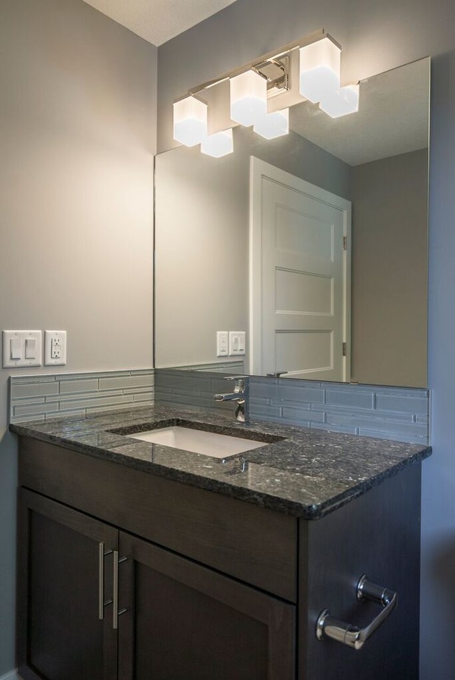 This is an example of a medium sized traditional shower room bathroom in Other with shaker cabinets, brown cabinets, an alcove bath, an alcove shower, a two-piece toilet, grey tiles, glass tiles, grey walls, laminate floors, a submerged sink, quartz worktops, grey floors and a shower curtain.