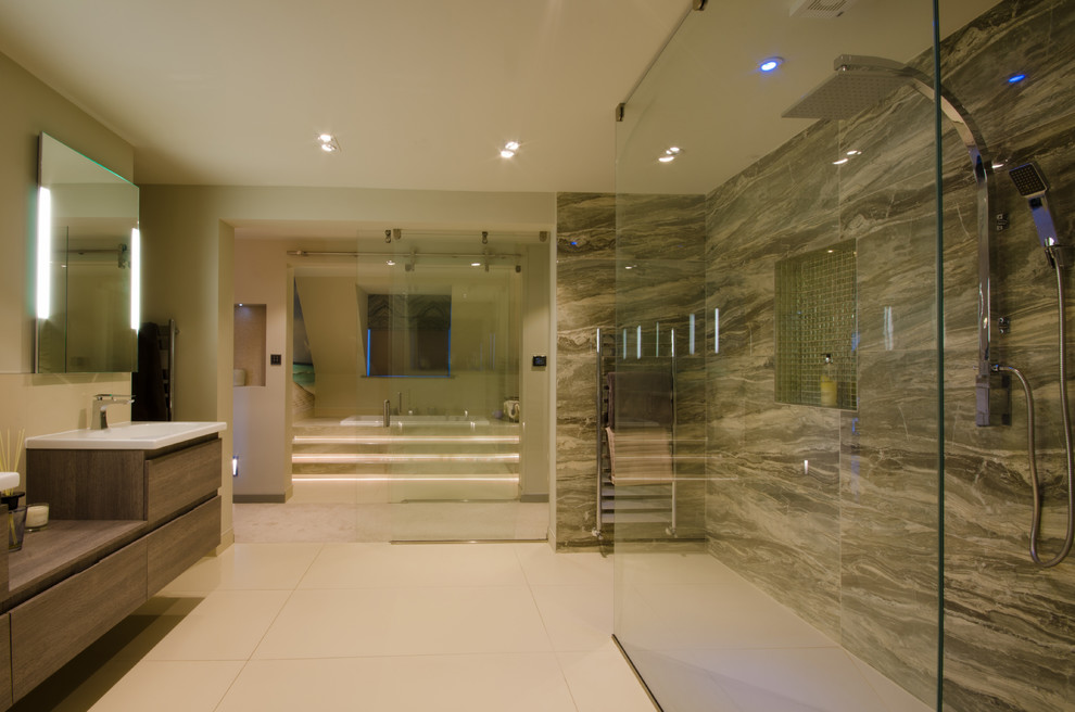 Example of a large trendy 3/4 green tile and porcelain tile porcelain tile and gray floor bathroom design in West Midlands with flat-panel cabinets, medium tone wood cabinets, an undermount tub, a wall-mount toilet, gray walls, a wall-mount sink and wood countertops