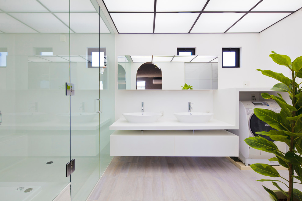 Réalisation d'une salle de bain minimaliste avec une vasque, un placard à porte plane, des portes de placard blanches, un mur blanc, parquet clair, un sol beige et buanderie.
