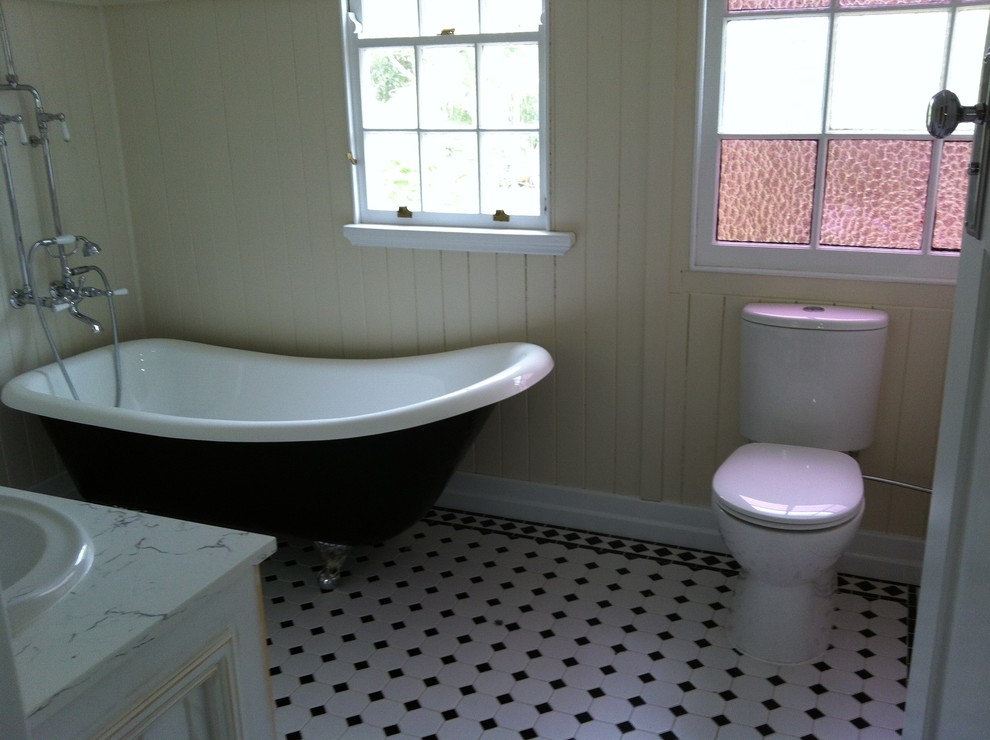 Bild på ett rustikt en-suite badrum, med luckor med upphöjd panel, skåp i slitet trä, ett badkar med tassar, en dusch/badkar-kombination, svart och vit kakel, klinkergolv i keramik, ett nedsänkt handfat, en toalettstol med separat cisternkåpa, mosaik, beige väggar, bänkskiva i kvarts, vitt golv och med dusch som är öppen