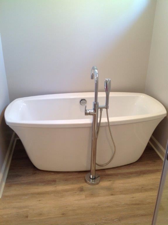 Immagine di una stanza da bagno minimal con vasca freestanding, pareti bianche, pavimento in legno massello medio e pavimento marrone