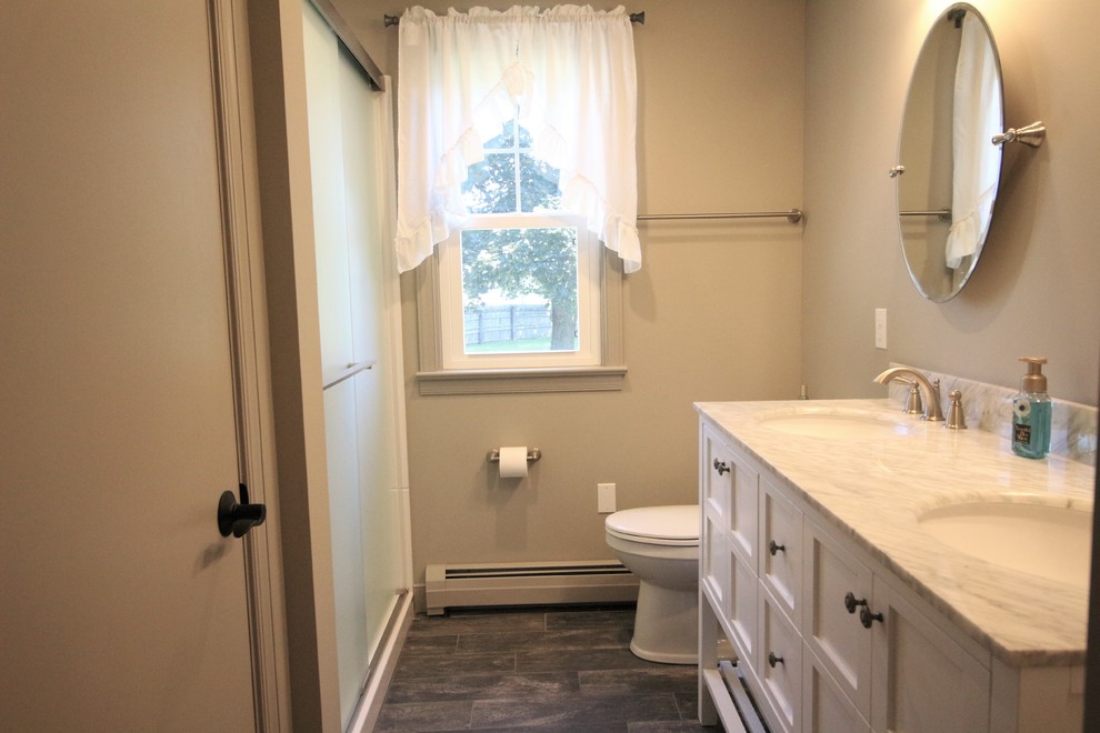 Foto på ett litet vintage en-suite badrum, med släta luckor, vita skåp, en dusch i en alkov, en toalettstol med hel cisternkåpa, grå väggar, klinkergolv i porslin, ett undermonterad handfat, marmorbänkskiva, grått golv och dusch med skjutdörr