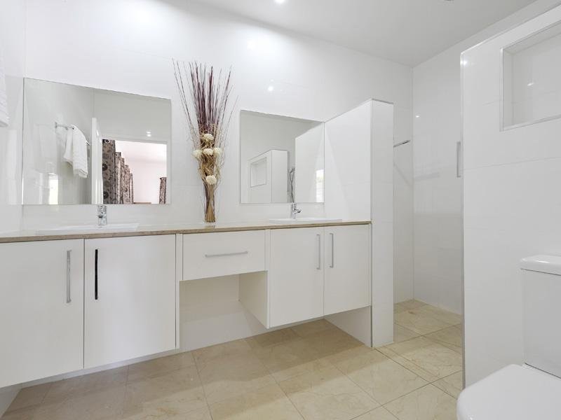 Medium sized contemporary ensuite bathroom in Brisbane with raised-panel cabinets, white cabinets, a double shower, a one-piece toilet, white tiles, ceramic tiles, white walls, marble flooring, a built-in sink and marble worktops.