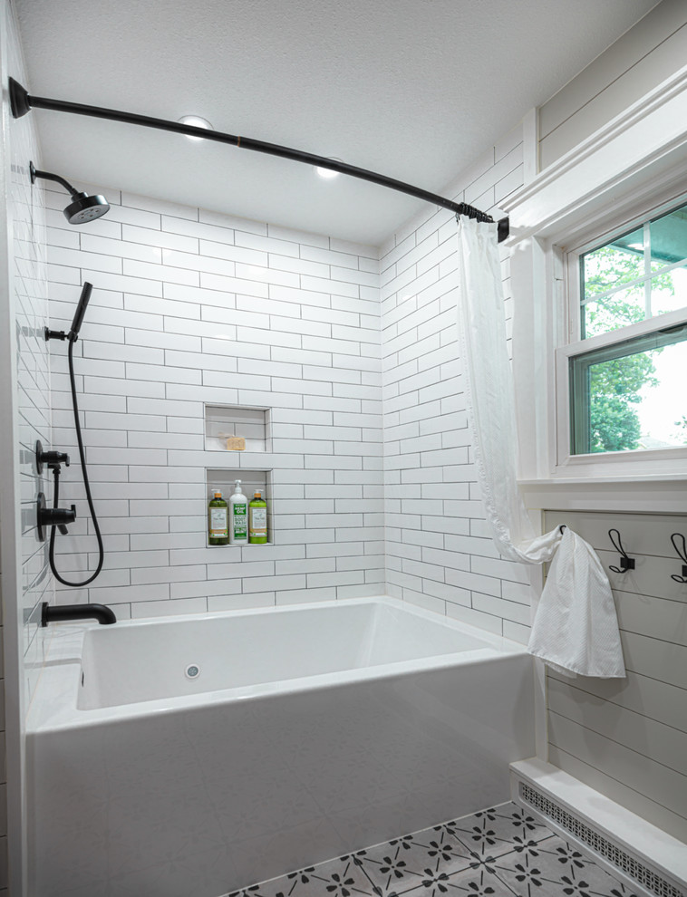 Lantlig inredning av ett mellanstort badrum, med skåp i mellenmörkt trä, ett badkar i en alkov, en dusch/badkar-kombination, en toalettstol med separat cisternkåpa, vit kakel, keramikplattor, grå väggar, klinkergolv i porslin, träbänkskiva, grått golv, dusch med duschdraperi och ett fristående handfat