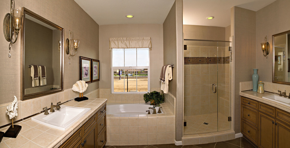 Пример оригинального дизайна: большая главная ванная комната в стиле неоклассика (современная классика) с фасадами с выступающей филенкой, фасадами цвета дерева среднего тона, столешницей из плитки, угловой ванной, угловым душем, бежевой плиткой, полом из керамической плитки, бежевыми стенами, керамической плиткой, накладной раковиной, коричневым полом и душем с распашными дверями