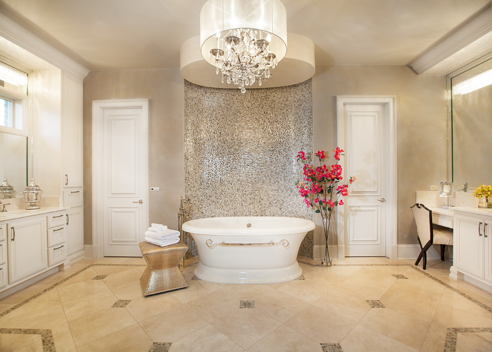 Exemple d'une grande salle de bain principale chic avec un placard avec porte à panneau encastré, des portes de placard blanches, une baignoire indépendante, mosaïque, un mur beige, un sol en travertin, un lavabo encastré et un sol beige.