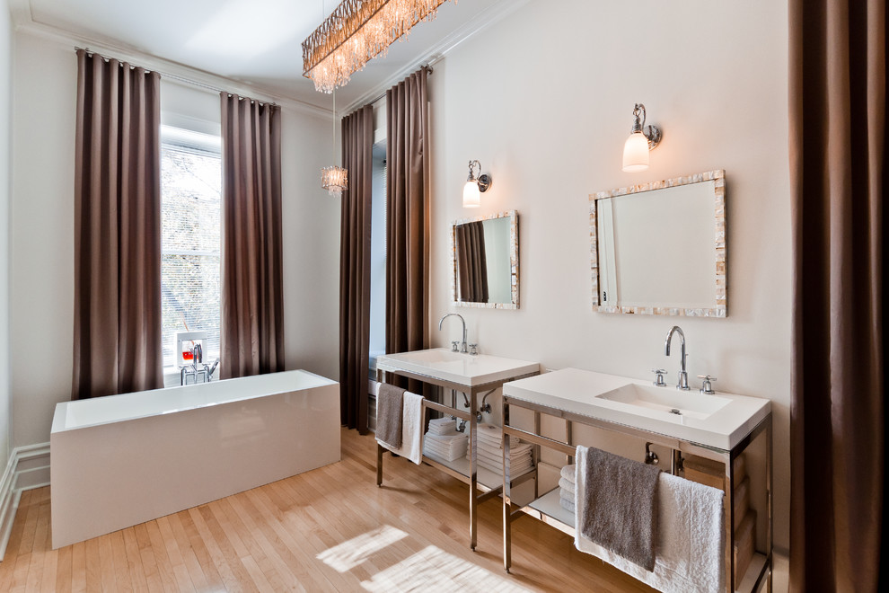 Cette image montre une salle de bain principale design de taille moyenne avec une baignoire indépendante, un mur blanc, parquet clair, un lavabo intégré, un plan de toilette en quartz modifié et un sol marron.