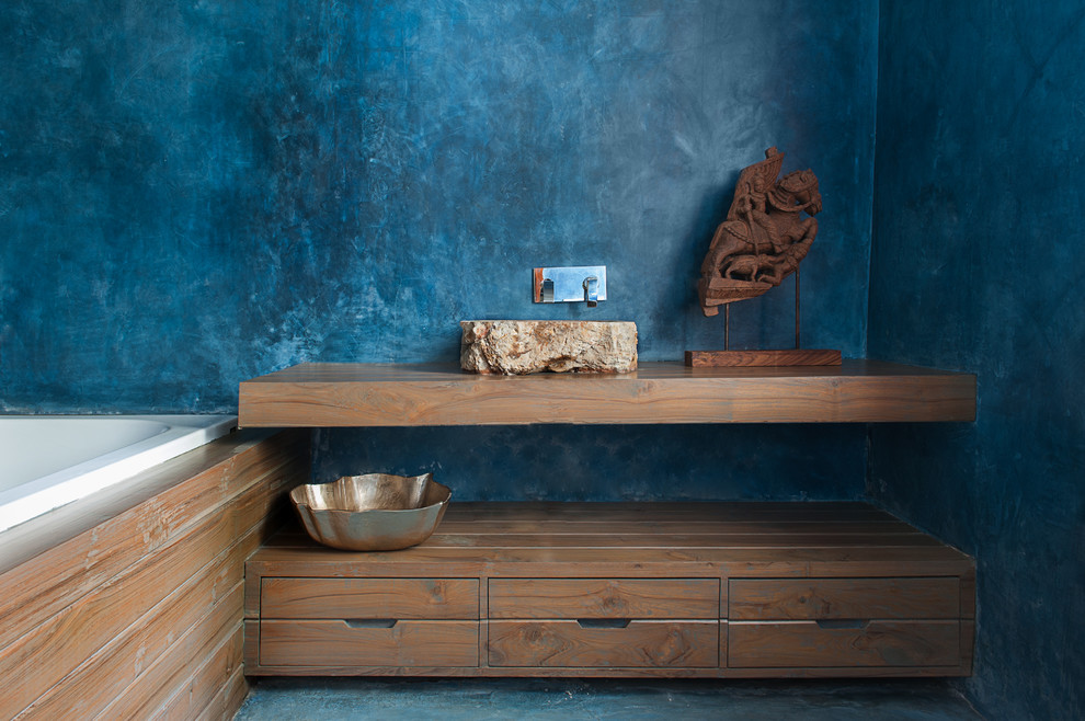Asiatisches Badezimmer mit offenen Schränken, hellbraunen Holzschränken, Einbaubadewanne, blauer Wandfarbe, Waschtisch aus Holz und brauner Waschtischplatte in Delhi