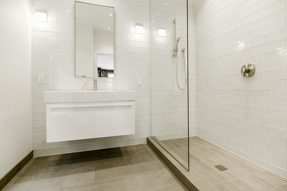 Diseño de cuarto de baño pequeño con puertas de armario blancas, ducha abierta, baldosas y/o azulejos blancos, baldosas y/o azulejos de vidrio, paredes blancas, suelo de cemento, aseo y ducha y lavabo suspendido