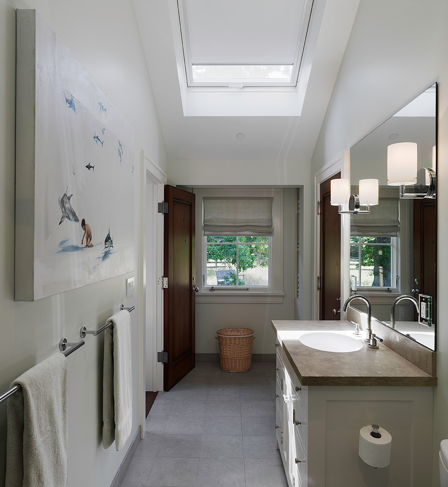 Inspiration pour une salle de bain principale traditionnelle avec un lavabo encastré, un carrelage gris, un placard à porte plane, des portes de placard blanches et un sol en calcaire.