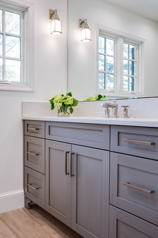 Example of a mid-sized transitional white tile and ceramic tile laminate floor, brown floor and single-sink bathroom design in DC Metro with flat-panel cabinets, gray cabinets, a one-piece toilet, white walls, a drop-in sink, marble countertops, white countertops and a freestanding vanity