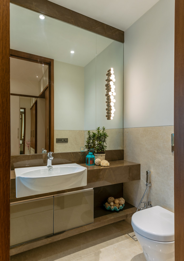 Exemple d'une petite salle d'eau tendance avec un placard à porte plane, des portes de placard marrons, WC suspendus, un carrelage beige, un mur blanc, un lavabo posé, un sol beige et un plan de toilette marron.