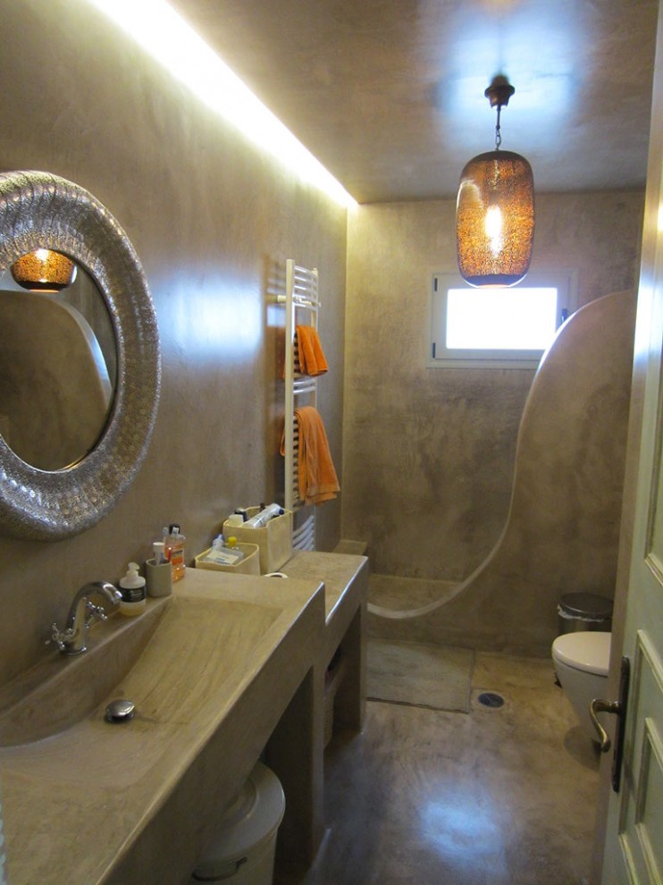 Idées déco pour une douche en alcôve principale méditerranéenne avec un lavabo suspendu, un plan de toilette en béton, WC suspendus, un mur beige et sol en béton ciré.