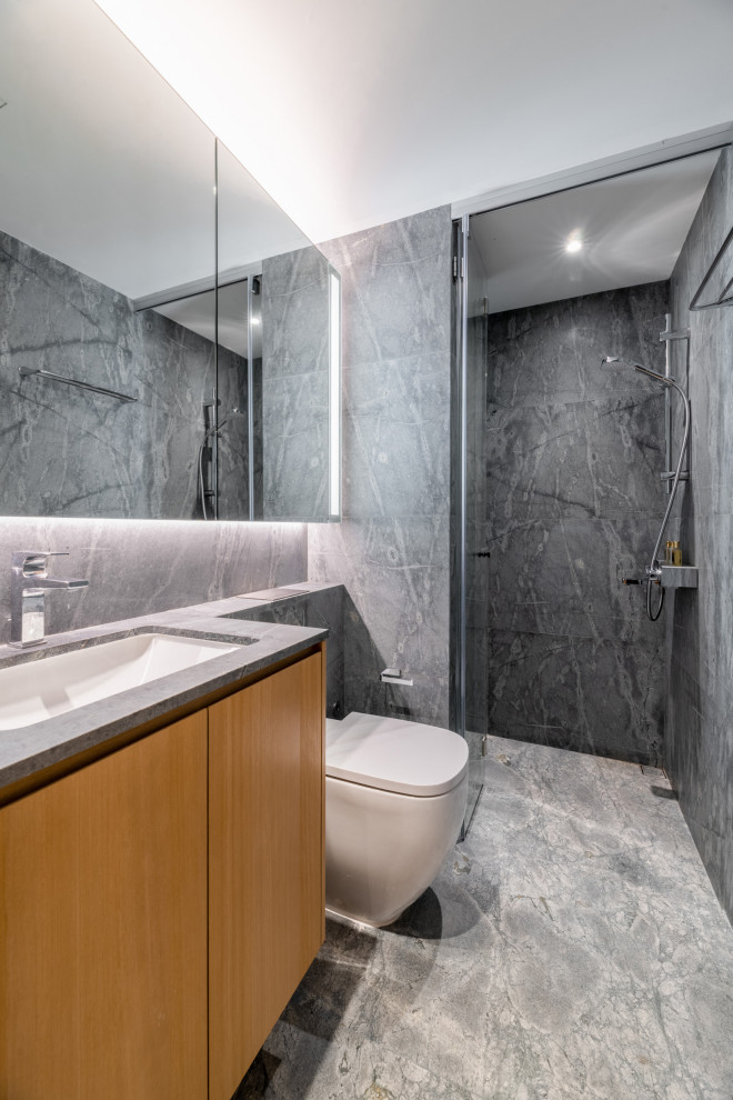 Walk-in shower - contemporary gray tile gray floor and single-sink walk-in shower idea in Singapore with flat-panel cabinets, medium tone wood cabinets, a one-piece toilet, an undermount sink, a hinged shower door and gray countertops