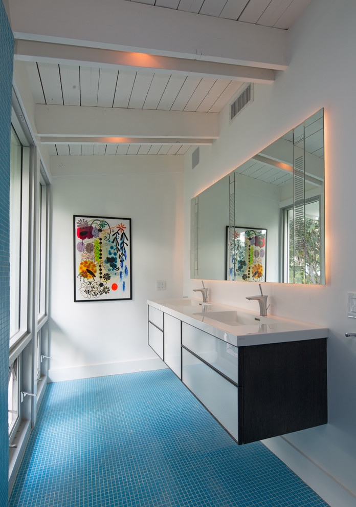 Ejemplo de cuarto de baño actual con lavabo integrado, armarios con paneles lisos, puertas de armario blancas, baldosas y/o azulejos azules, paredes blancas, suelo azul y encimeras blancas