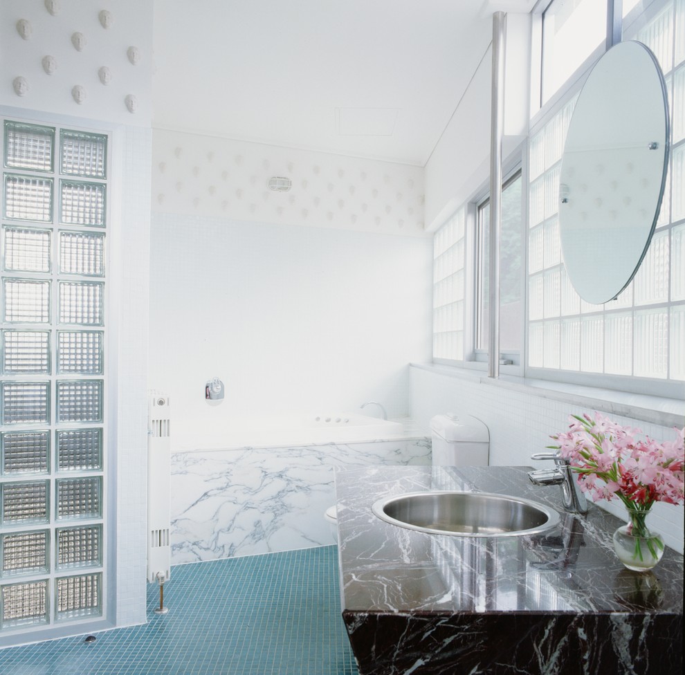Ispirazione per una stanza da bagno minimalista di medie dimensioni con vasca ad alcova, pavimento con piastrelle a mosaico, lavabo da incasso e top in marmo