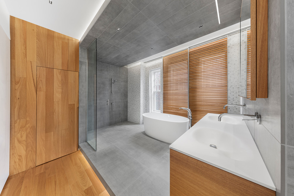 Foto de cuarto de baño principal contemporáneo de tamaño medio con bañera exenta, ducha abierta, baldosas y/o azulejos grises, paredes grises y lavabo integrado