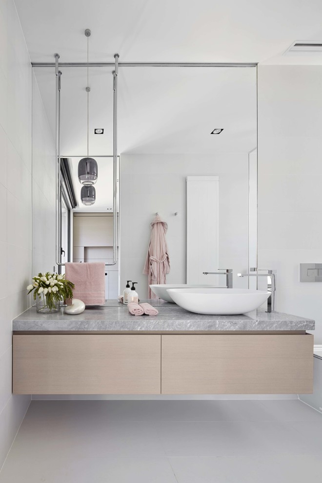 Inredning av ett modernt grå grått badrum, med släta luckor, skåp i ljust trä, vita väggar, ett fristående handfat och vitt golv