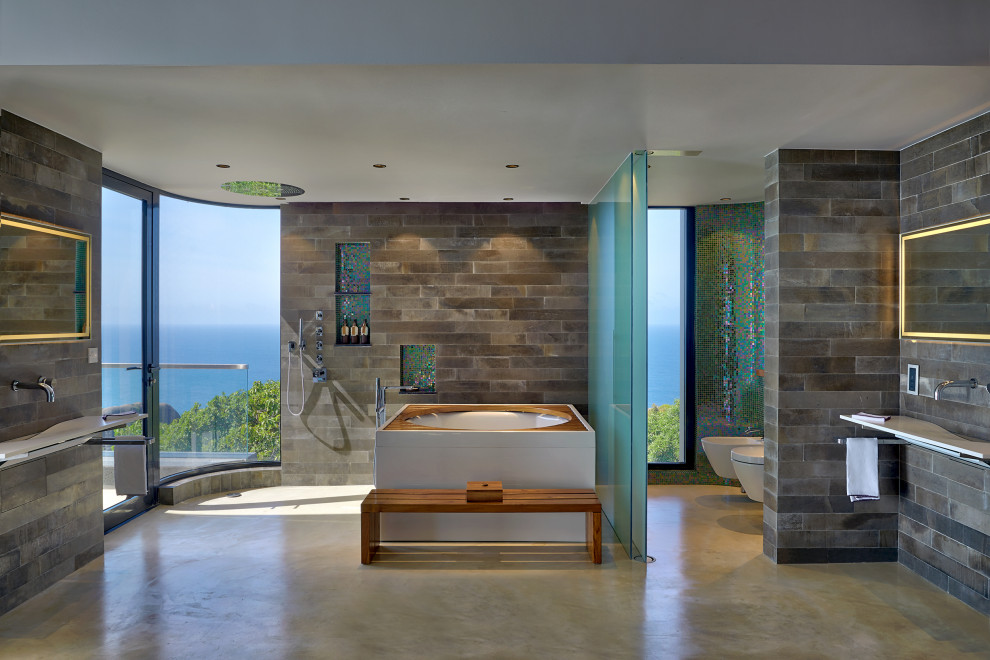 Example of an island style master multicolored tile gray floor bathroom design in London with a hot tub and an integrated sink