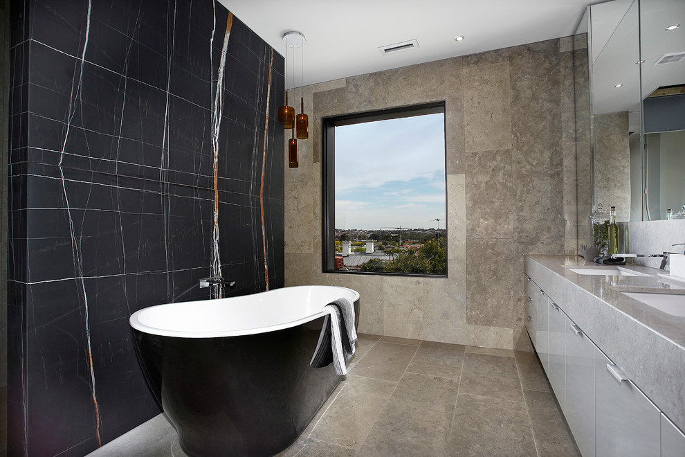 Trendy limestone tile freestanding bathtub photo in Melbourne with black walls and gray countertops