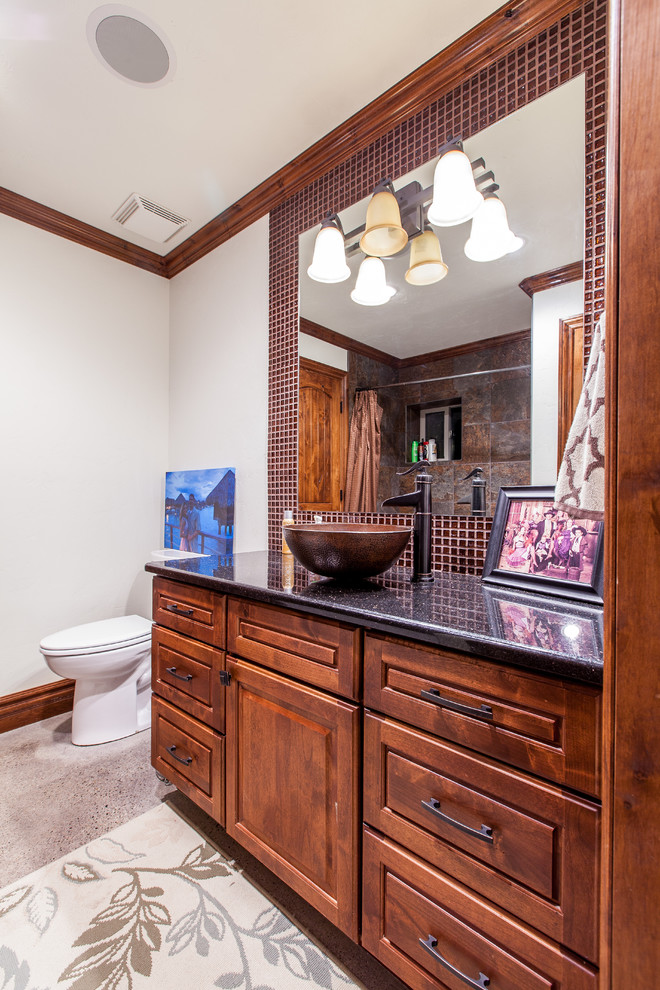 Cette photo montre une salle d'eau moderne en bois foncé de taille moyenne avec un placard avec porte à panneau surélevé, WC séparés, un carrelage rouge, mosaïque, sol en béton ciré, une vasque et un plan de toilette en granite.