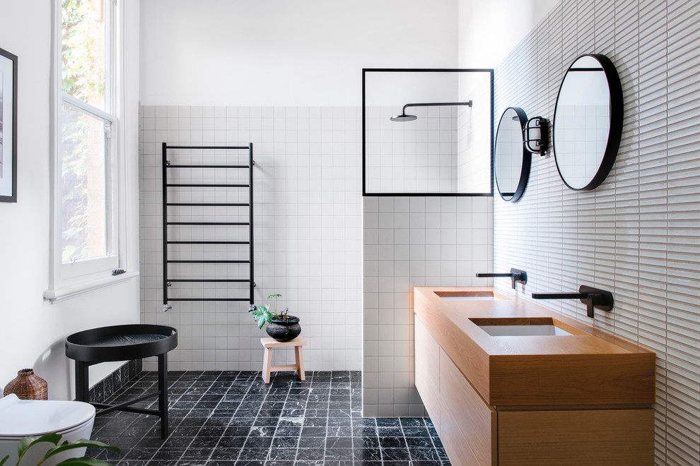 Foto på ett funkis badrum, med släta luckor, skåp i ljust trä, en öppen dusch, en toalettstol med hel cisternkåpa, vita väggar, träbänkskiva och med dusch som är öppen