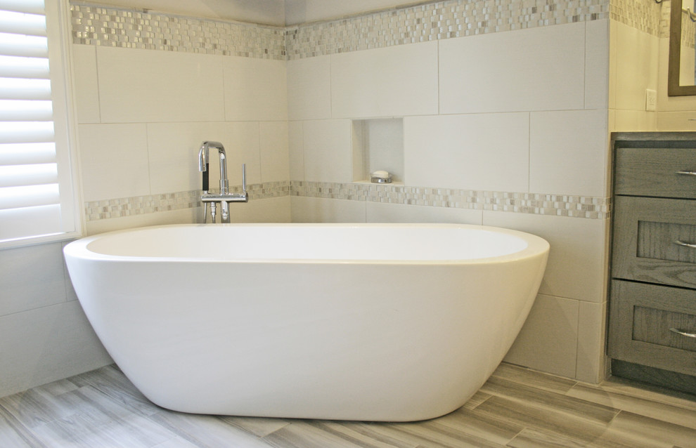 Example of a large transitional master gray tile and ceramic tile ceramic tile freestanding bathtub design in Charleston with shaker cabinets, gray cabinets, granite countertops and gray walls