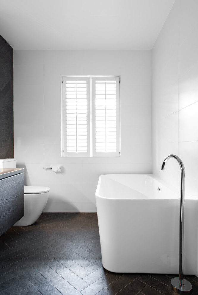 Cette image montre une salle de bain principale design avec une douche d'angle, un carrelage gris, un mur blanc, un sol gris et aucune cabine.