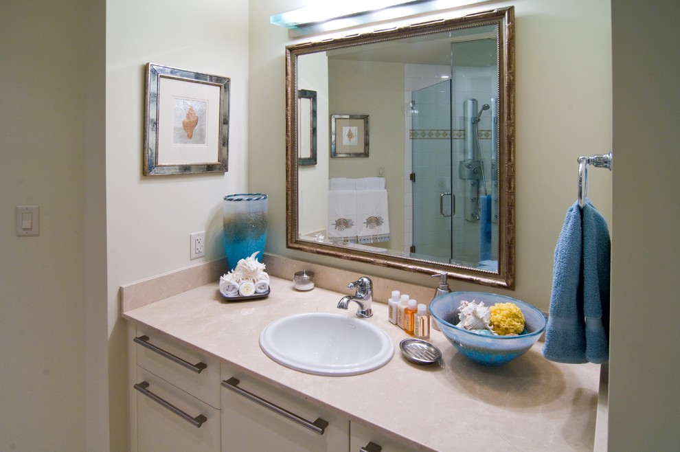 Ejemplo de cuarto de baño tropical con armarios con paneles lisos, puertas de armario blancas, ducha esquinera, sanitario de una pieza, baldosas y/o azulejos beige, baldosas y/o azulejos de piedra, paredes beige, suelo de piedra caliza, lavabo encastrado y encimera de piedra caliza