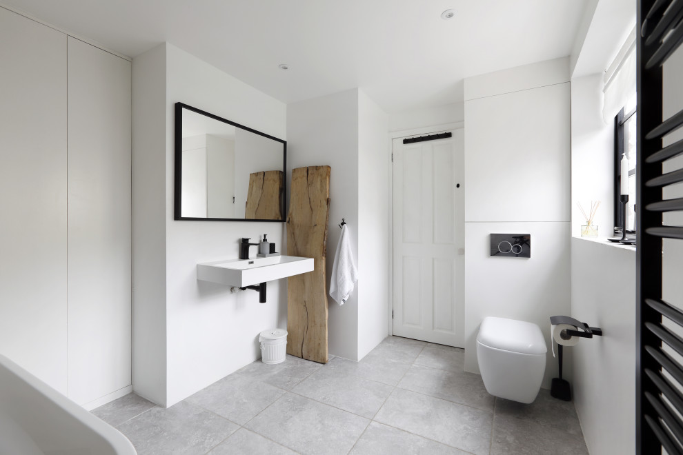 Bild på ett mellanstort funkis badrum för barn, med ett fristående badkar, en vägghängd toalettstol, vita väggar, ett väggmonterat handfat, grått golv, en öppen dusch, klinkergolv i keramik och med dusch som är öppen