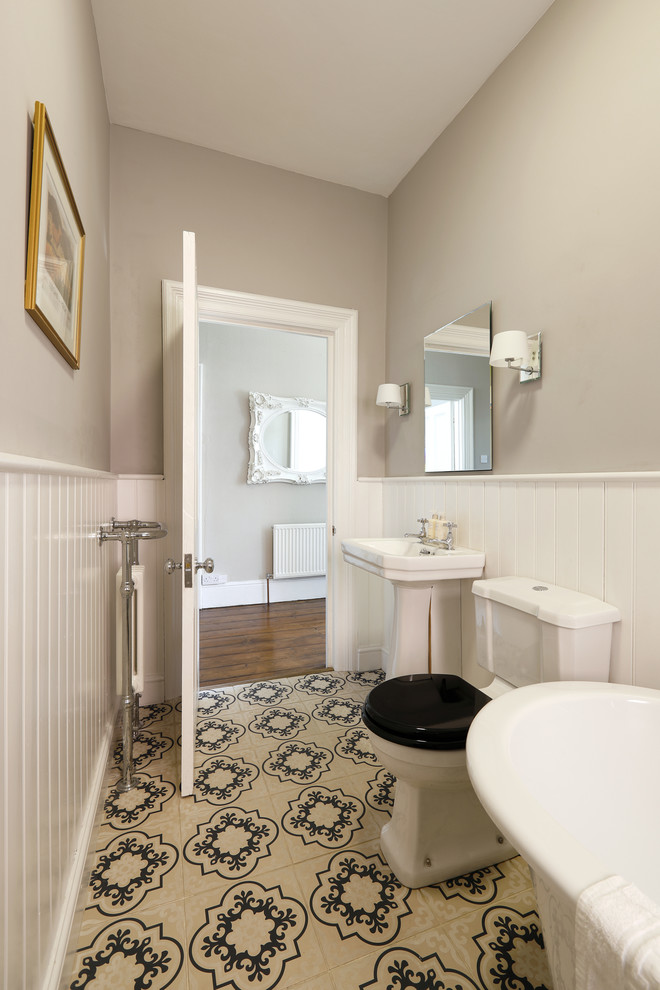 Medium sized traditional family bathroom in Sussex with a freestanding bath, a two-piece toilet, beige walls, ceramic flooring, a pedestal sink and multi-coloured floors.