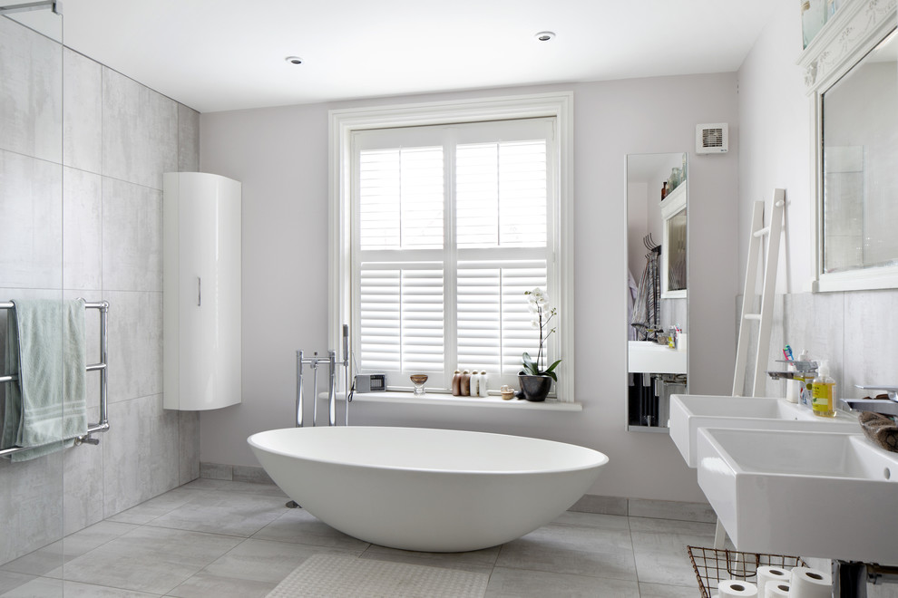 Inspiration for a large scandi family bathroom in Sussex with flat-panel cabinets, white cabinets, a freestanding bath, grey tiles, ceramic tiles, a walk-in shower, a wall-mounted sink, a wall mounted toilet, grey walls and ceramic flooring.