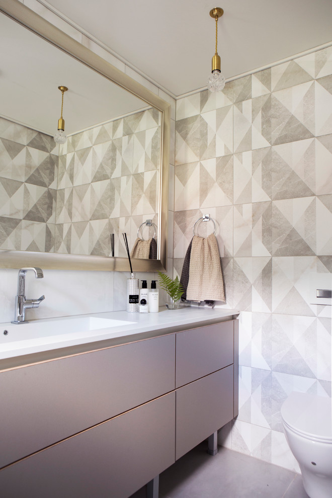 Imagen de cuarto de baño actual con armarios con paneles lisos, puertas de armario grises, sanitario de pared, paredes beige y lavabo integrado