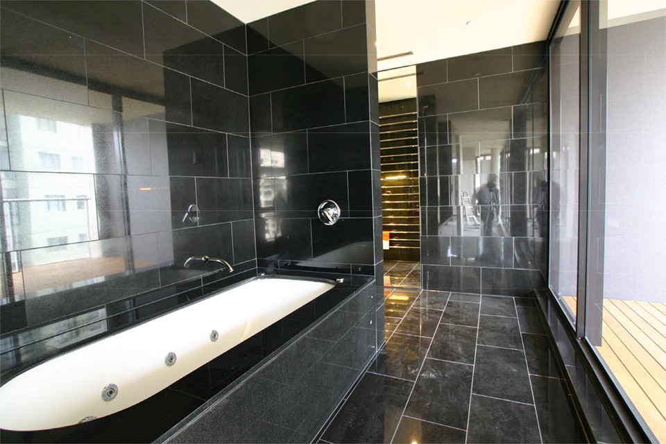 Пример оригинального дизайна: огромная ванная комната в современном стиле с ванной в нише, плиткой из листового камня, черными стенами и полом из известняка