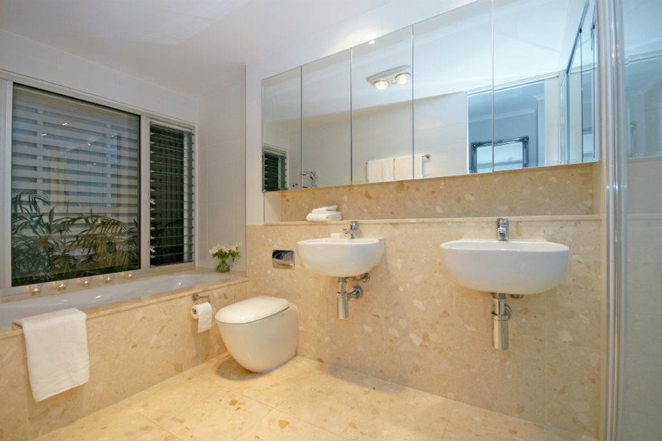 Стильный дизайн: детская ванная комната в стиле модернизм с белыми фасадами, двойным душем, инсталляцией, бежевой плиткой, каменной плиткой, белыми стенами, полом из керамогранита, подвесной раковиной и столешницей из плитки - последний тренд