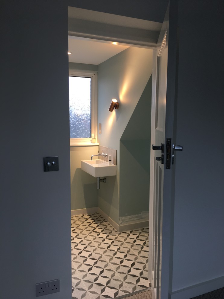 Idéer för små funkis en-suite badrum, med en hörndusch, en vägghängd toalettstol, beige kakel, porslinskakel, gröna väggar, klinkergolv i keramik, ett väggmonterat handfat och dusch med gångjärnsdörr