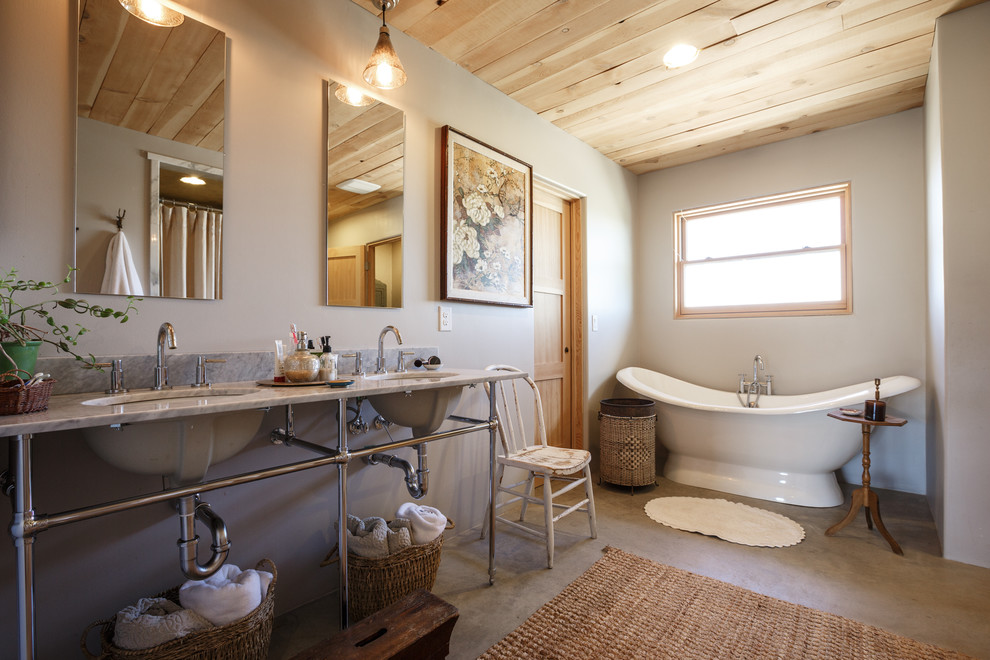 Idéer för att renovera ett badrum, med ett undermonterad handfat, ett fristående badkar, grå väggar och betonggolv