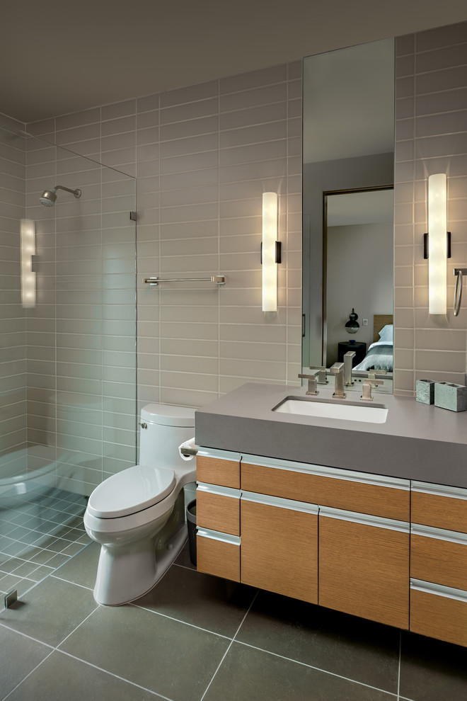 Идея дизайна: ванная комната в современном стиле с плоскими фасадами, фасадами цвета дерева среднего тона, душем в нише, унитазом-моноблоком, серой плиткой, душевой кабиной, врезной раковиной, серым полом, серой столешницей, плиткой кабанчик и серыми стенами