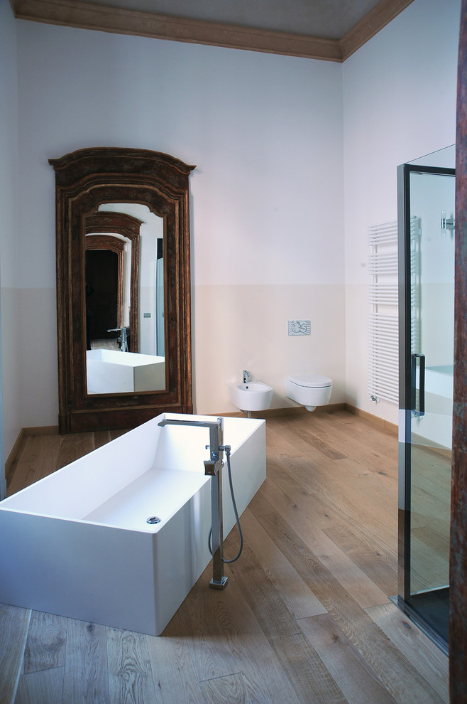 Idéer för stora funkis en-suite badrum, med ett väggmonterat handfat, ett fristående badkar, en hörndusch, en bidé och ljust trägolv
