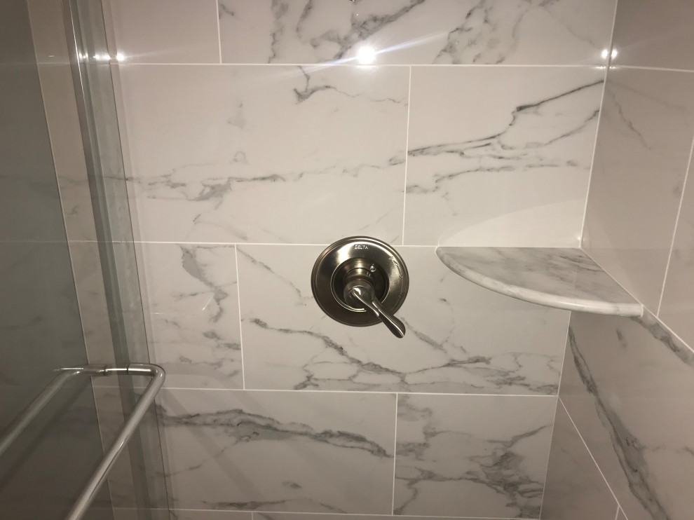 This is an example of a medium sized contemporary ensuite bathroom in DC Metro with shaker cabinets, white cabinets, an alcove shower, a two-piece toilet, white tiles, porcelain tiles, grey walls, porcelain flooring, a submerged sink, quartz worktops, white floors, a sliding door, grey worktops, a wall niche, double sinks and a built in vanity unit.