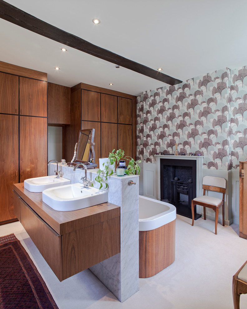 Photo of a contemporary bathroom in London with a vessel sink, flat-panel cabinets, medium wood cabinets, a freestanding bath, multi-coloured walls and a chimney breast.