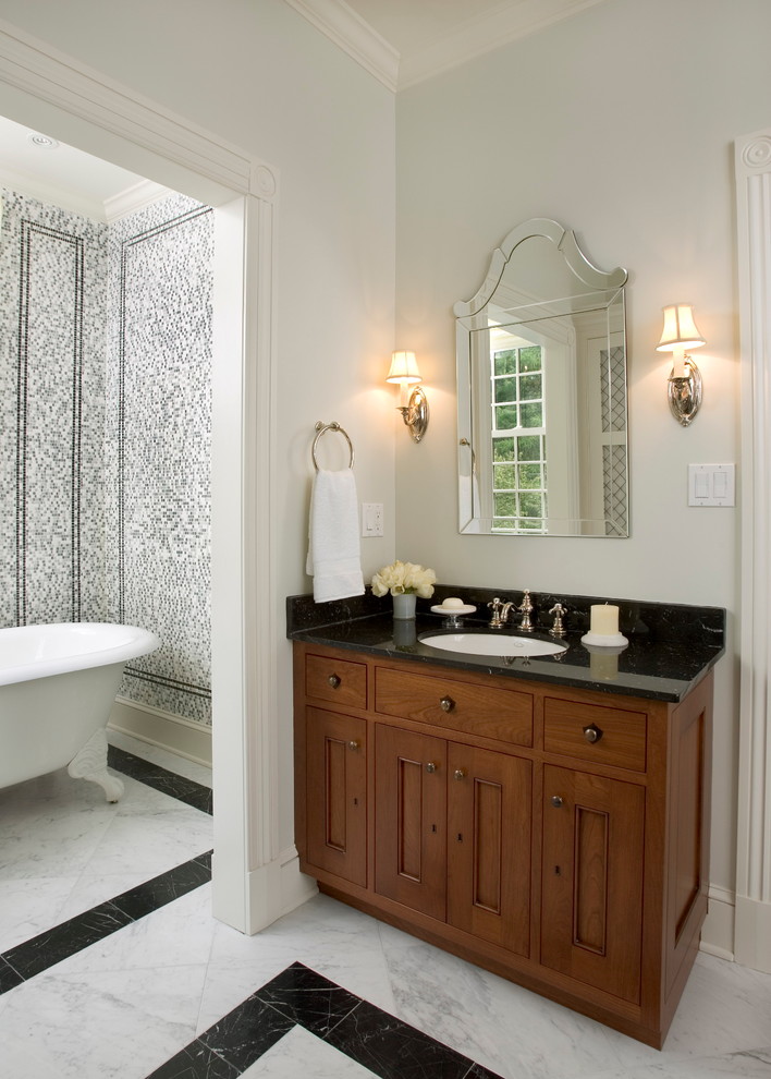 Aménagement d'une salle de bain principale classique en bois brun avec une baignoire sur pieds, mosaïque, un placard à porte shaker, un mur blanc, un sol en marbre, un lavabo encastré, un plan de toilette en marbre et un sol blanc.