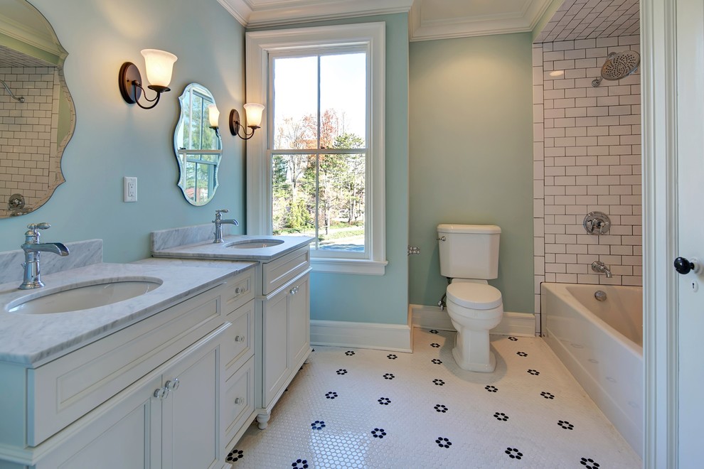 Modelo de cuarto de baño infantil clásico con puertas de armario blancas, bañera empotrada, baldosas y/o azulejos blancos, lavabo bajoencimera y encimera de mármol