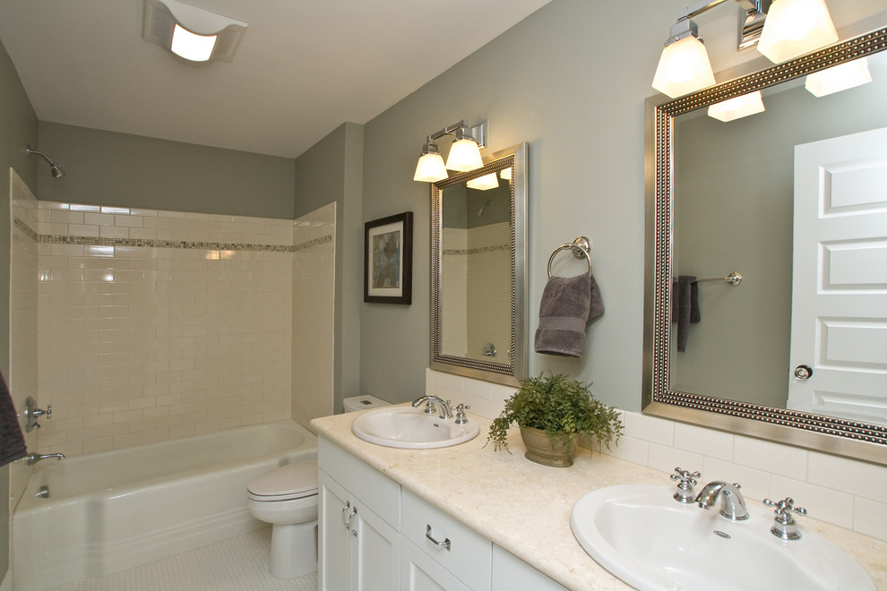 Mid-sized elegant white tile and subway tile porcelain tile bathroom photo in Portland with a drop-in sink, recessed-panel cabinets, white cabinets, marble countertops and gray walls