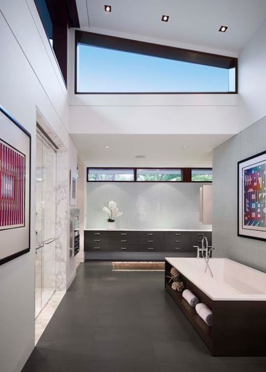 This is an example of a large modern ensuite bathroom in Chicago with flat-panel cabinets, black cabinets, a freestanding bath, a walk-in shower, a one-piece toilet, white tiles, marble tiles, white walls, cement flooring, a built-in sink, granite worktops, black floors and an open shower.