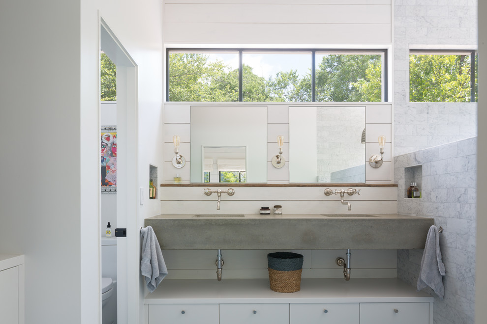 Réalisation d'une salle de bain champêtre avec un placard à porte plane, des portes de placard blanches, un carrelage blanc, un mur blanc, un lavabo intégré, un plan de toilette en béton et un plan de toilette gris.