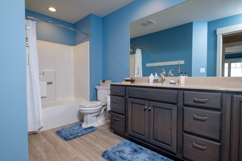 Foto på ett litet vintage en-suite badrum, med ett badkar i en alkov, en dusch/badkar-kombination, en toalettstol med separat cisternkåpa, blå väggar, ett undermonterad handfat, granitbänkskiva, luckor med upphöjd panel, skåp i mörkt trä och vinylgolv