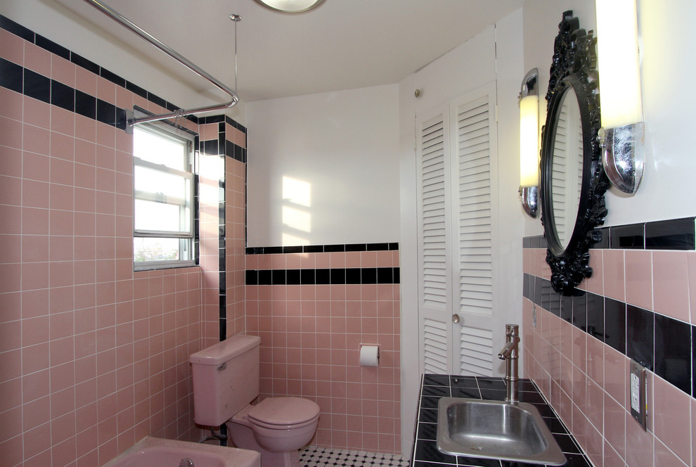 Ispirazione per una piccola stanza da bagno con doccia minimalista con lavabo da incasso, ante con riquadro incassato, ante nere, top piastrellato, vasca ad angolo, WC a due pezzi, piastrelle nere, piastrelle in ceramica, pareti rosa e pavimento con piastrelle a mosaico